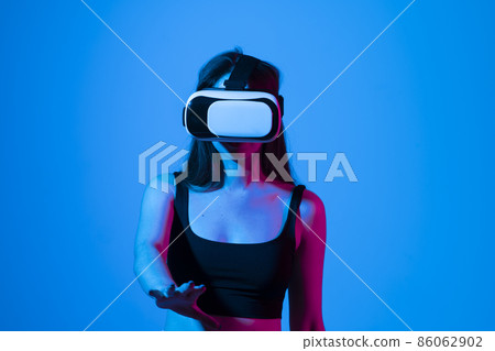 Smile happy woman getting experience using vr-headset glasses of virtual reality much gesticulating hands on gray background. Girl spend shes time in metaverse. Smile happy woman getting experience using vr-headset glasses of virtual reality much gesticulating hands on gray background. Girl spend shes time in metaverse. 86062902