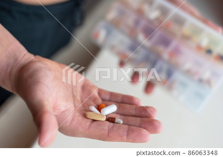 Closeup of a male palm with pills. A man takes a daily dose of vitamins and nutritional supplements from a daily pill box. Closeup of a male palm with pills. A man takes a daily dose of vitamins and nutritional supplements from a daily pill box. 86063348