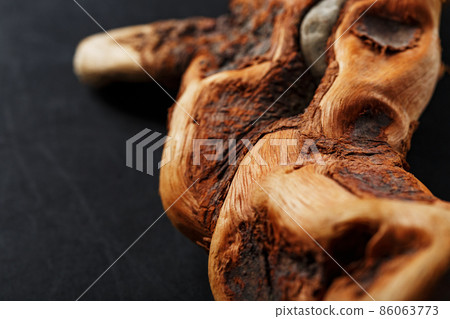 Textured curved Wooden snag of brown color with texture on a black background. 86063773
