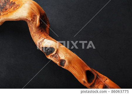 Textured curved Wooden snag of brown color with texture on a black background with free space. 86063775