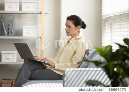 Concentrated mature middle aged woman working on computer. Concentrated mature middle aged woman working on computer. 86064673