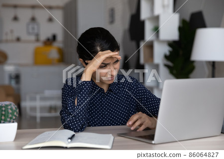 Tired upset Indian business woman working at laptop computer 86064827