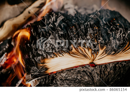 Old open book is burning. Big bright flame on papers. Destruction of diary in fireplace Old open book is burning. Big bright flame on papers. Destruction of diary in fireplace 86065154