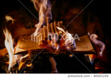 Old open book is burning. Big bright flame on papers. Destruction of diary in fireplace Old open book is burning. Big bright flame on papers. Destruction of diary in fireplace 86065209