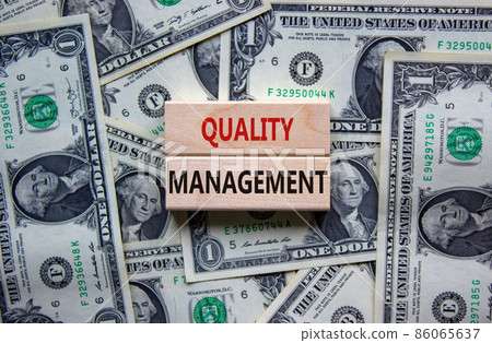Quality management symbol. Concept words 'Quality management' on wooden blocks on a beautiful background from dollar bills. Business and quality management concept. Quality management symbol. Concept words 'Quality management' on wooden blocks on a beautiful background from dollar bills. Business and quality management concept. 86065637