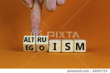 Altruism or egoism symbol. Businessman turns wooden cubes and changes the word 'egoism' to 'altruism'. Beautiful orange background, copy space. Business, psychological and altruism or egoism concept. 86065729
