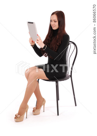 Girl sits on a chair and looking at tablet pc Girl sits on a chair and looking at tablet pc 86066570