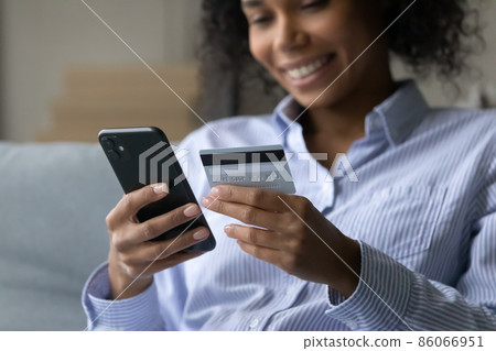 Close up smiling African woman purchasing goods in mobile shopping app. 86066951