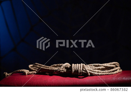 Skein of rope for role-playing games on a red leather couch. BDSM concept. A lace for the Japanese art of shibari. No people. 86067382