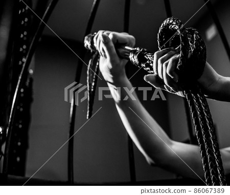 BDSM concept. A woman in a leather corset holds a black lash with a long fringe. Role-playing games for adults. Close-up of sex toys for domination. The whip in female hands. BDSM concept. A woman in a leather corset holds a black lash with a long fringe. Role-playing games for adults. Close-up of sex toys for domination. The whip in female hands. 86067389