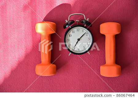 Two orange tunnels and an alarm clock on a pink yoga mat. Time to do fitness at home with equipment. Quarantine sports discipline 86067464