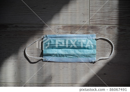 A medical mask lies on a wooden surface. Personal hygiene products and respiratory tract protection. Coronavirus Prevention 86067491