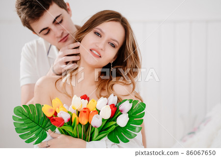 a man gave his beloved woman a bouquet of colorful tulips. tender embrace. 86067650