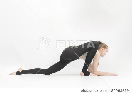 Young slender gymnast girl does an exercise to develop flexibility on white background. Asanas in yoga. Young slender gymnast girl does an exercise to develop flexibility on white background. Asanas in yoga. 86068219