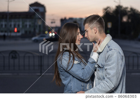 Young beautiful caucasian couple hugging on the background of the evening city. Side view Young beautiful caucasian couple hugging on the background of the evening city. Side view 86068303