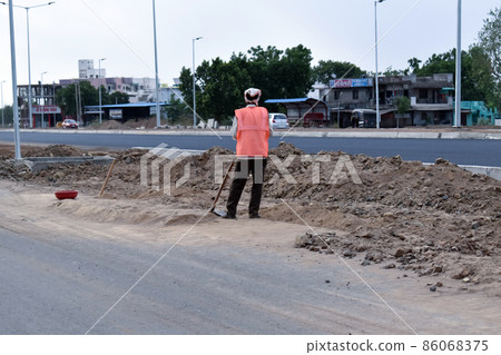 Labor is ready with a shovel to remove the soil on the side of the asphalt road Labor is ready with a shovel to remove the soil on the side of the asphalt road 86068375