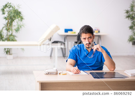 Young male doctor sitting in the clinic Young male doctor sitting in the clinic 86069292