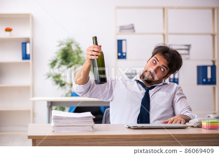 Young alcohol addicted employee sitting in the office 86069409