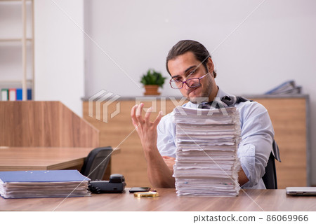 Young male employee unhappy with excessive work in the office 86069966