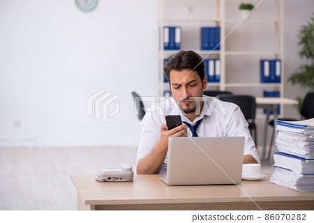 Young male employee unhappy with excessive work in the office Young male employee unhappy with excessive work in the office 86070282