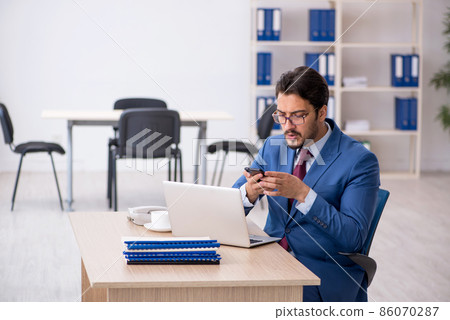 Young male employee sitting at workplace 86070287