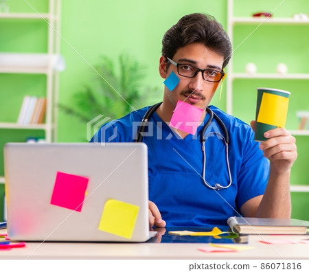Young doctor sitting in hospital with many conflicting prioritie Young doctor sitting in hospital with many conflicting prioritie 86071816