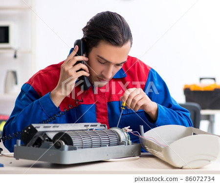Young repairman repairing air-conditioner at warranty center Young repairman repairing air-conditioner at warranty center 86072734