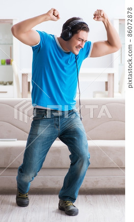 Young handsome man listening to the music and having fun at home Young handsome man listening to the music and having fun at home 86072878
