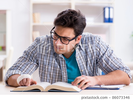 Young student man with hand injury preparing for the exams Young student man with hand injury preparing for the exams 86073346