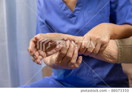Caregiver massaging wrist of elderly woman in painful swollen gout . 86073350