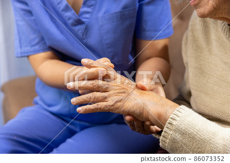 Caregiver massaging finger of elderly woman in painful swollen gout . 86073352