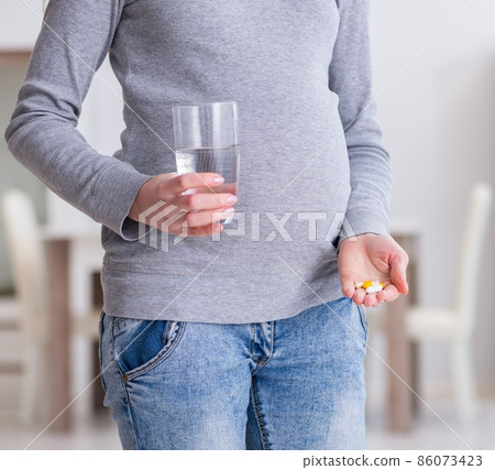 Pregnant woman taking pills during pregnancy 86073423