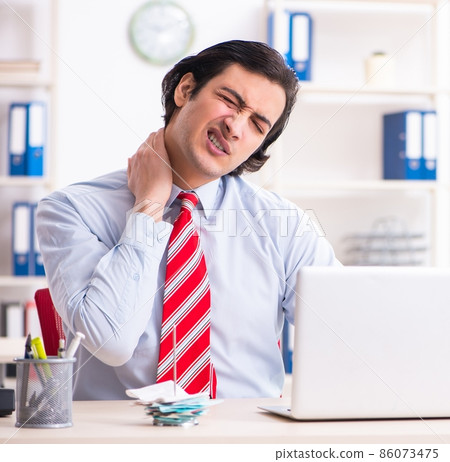 Young male employee suffering in the office Young male employee suffering in the office 86073475