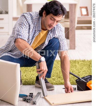 The young handsome man repairing chair at home The young handsome man repairing chair at home 86074478