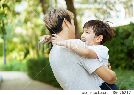 A little boy playing with his father at a park. A little boy playing with his father at a park. 86076217