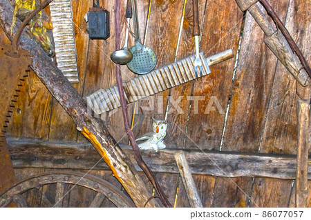 Different kind of vintage old kitchen utensils hung on wooden shelf in kitchen 86077057