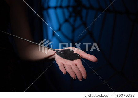 An unrecognizable woman demonstrates an elegant thin leather strip whip in a dark bedroom. Close-up of female hands with a bdsm toy. Pain and pleasure.Adult toy for slaps. 86079358