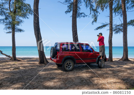 Young Asian male traveler and photographer standing on the car wheel 4x4 car and Taking photo sea beautiful beach in Phuket Thailand Travel photography concept Young Asian male traveler and photographer standing on the car wheel 4x4 car and Taking photo sea beautiful beach in Phuket Thailand Travel photography concept 86081150
