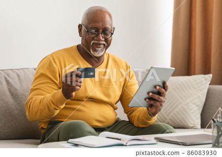Senior African Man Shopping Using Credit Card And Tablet Indoor Senior African Man Shopping Using Credit Card And Tablet Indoor 86083930