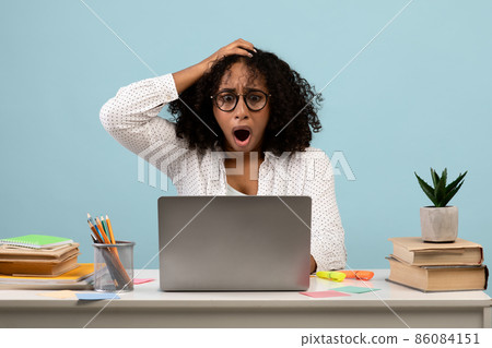 Deadline concept. Shocked black woman sitting at desk with laptop and grabbing her head, studying or working 86084151