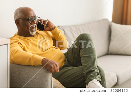 Senior African American Male Talking On Phone At Home, Side-View Senior African American Male Talking On Phone At Home, Side-View 86084153