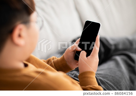 Over shoulder shot of chubby boy using cellphone, mockup Over shoulder shot of chubby boy using cellphone, mockup 86084156