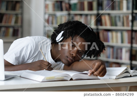 Tired bored lazy Black student listening to audio lesson Tired bored lazy Black student listening to audio lesson 86084299
