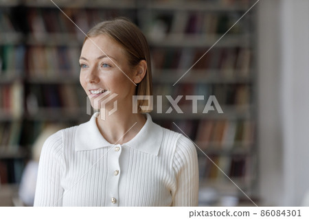 Happy thoughtful millennial university student girl standing in public library 86084301