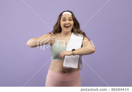 Cheerful cute excited caucasian plus size young female in sports uniform with fit tracker show thumb up Cheerful cute excited caucasian plus size young female in sports uniform with fit tracker show thumb up 86084414