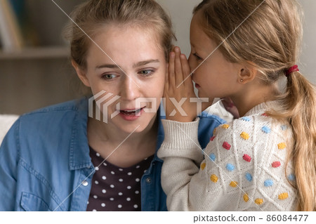 Joyful preteen girl telling secret to mum. 86084477