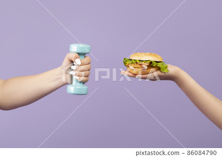 Caucasian plus size young woman hand hold dumbbell, slender hand offering burger Caucasian plus size young woman hand hold dumbbell, slender hand offering burger 86084790