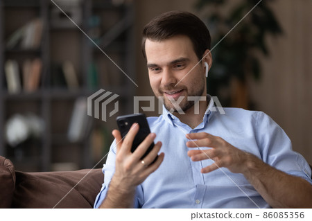 Head shot man in wireless headphones using smartphone, chatting online Head shot man in wireless headphones using smartphone, chatting online 86085356