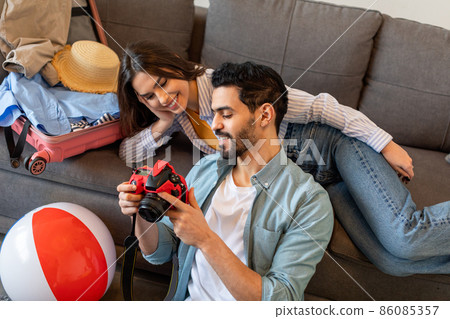 Loving spouses prerating for vacation, packing suitcase and using camera for watching photos in trip Loving spouses prerating for vacation, packing suitcase and using camera for watching photos in trip 86085357