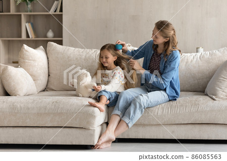 Relaxed mother detangling hair of little kid daughter. Relaxed mother detangling hair of little kid daughter. 86085563